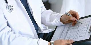 Doctor taking notes during a patient exam, focusing on early signs of medical conditions.