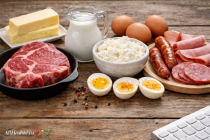 Foods commonly associated with higher cholesterol intake including red meat, full-fat dairy products, egg yolks, and processed meats displayed on a wooden table.